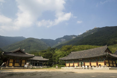 Houses on mountain against cloudy sky