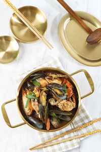 Korean soup jjampong, mix seafood spicy red noodle, chinese food. top view on gold pan