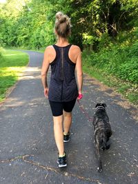 Rear view of woman with dog walking by plants