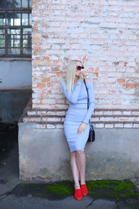 Full length of woman standing against brick wall