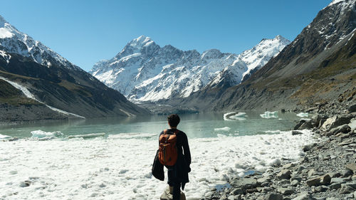 Rear view of man standing on snowcapped mountain