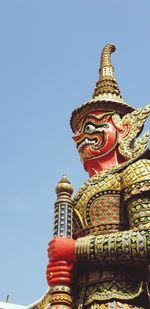 Low angle view of statue against temple building against clear sky