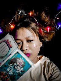 Close-up portrait of girl holding illuminated lighting equipment