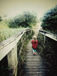 Rear view of woman walking on footbridge