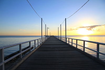 Pier over sea against sky during sunset
