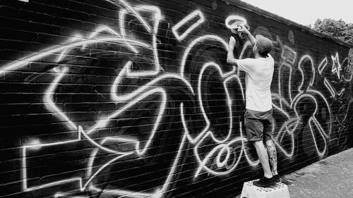 Midsection of woman standing by graffiti on wall at night