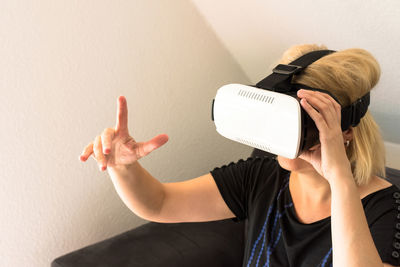 Woman pointing white using virtual reality simulator at home