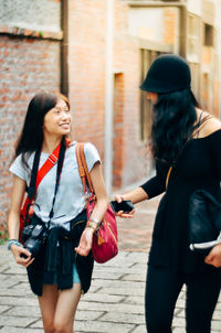 Happy friends walking on sidewalk in city