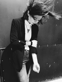 Young woman looking down while sitting on wall