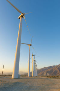 Wind turbines on field against clear sky