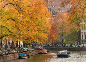 Boats in canal amidst buildings in city during autumn