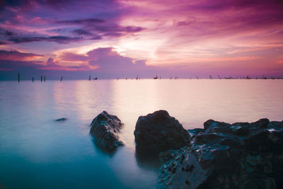 Scenic view of sea against cloudy sky at sunset