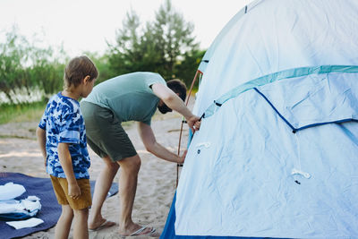 Cute little caucasian boy helping to put up a tent. family camping concept