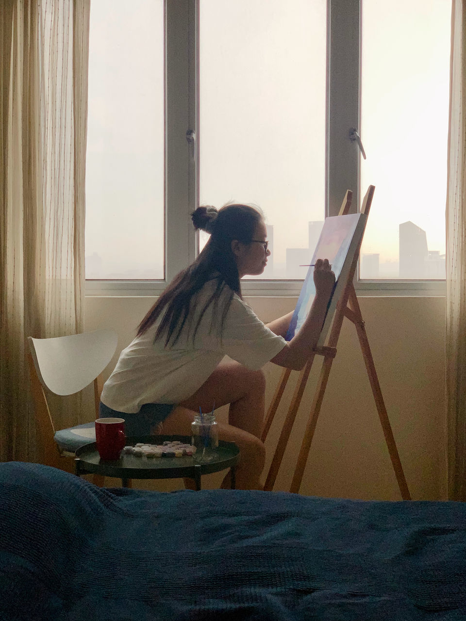 SIDE VIEW OF A YOUNG WOMAN SITTING ON TABLE