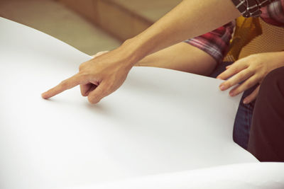 Cropped hand of woman pointing on blank paper at home