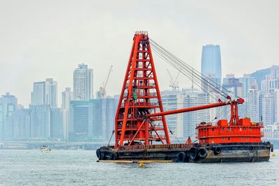 Construction site by sea against sky in city