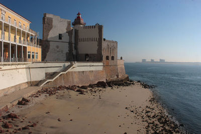 Buildings by sea against clear sky