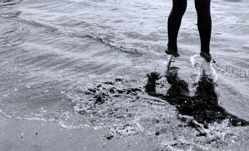 Low section of person jumping on shore at beach