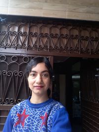 Portrait of smiling woman standing against wall