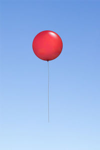 Low angle view of balloon flying against blue sky