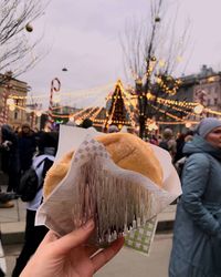 Cropped hand of person holding food by people in city