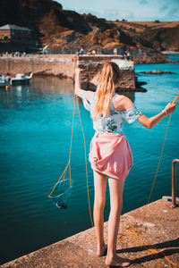 Rear view of woman fishing on pier in sea