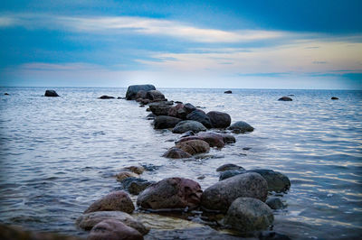 Rocks in sea against sky during sunset