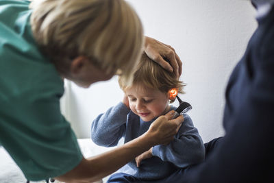 Female doctor examining boy's ear with otoscope in hospital