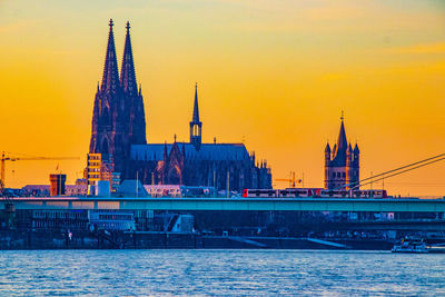 River amidst buildings against sky during sunset