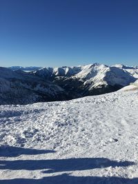 Scenic view of snowcapped mountains against clear blue sky