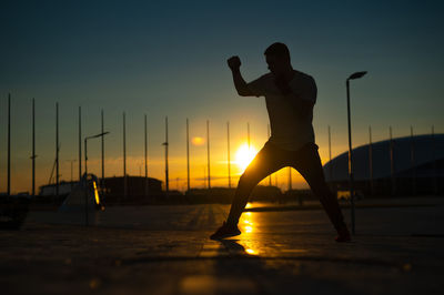 Side view of silhouette woman standing against sky during sunset