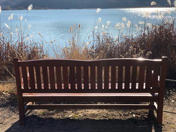 Empty bench on field by lake