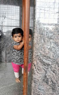 Portrait of girl standing against window