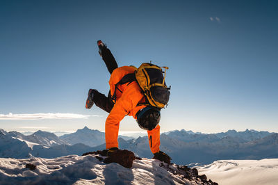 Skier upside down. handstand at the top of the mountain. athlete standing on his hands with his legs