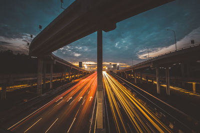 Light trails on highway in city against sky