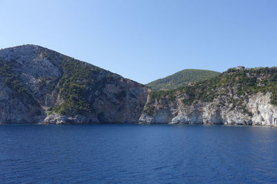 Scenic view of sea and mountains against clear blue sky