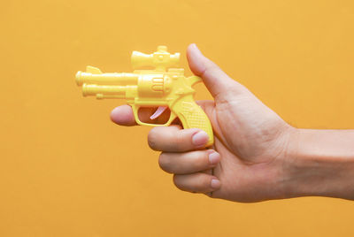Close-up of person hand against yellow background