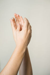 Cropped hands holding pearl against beige background