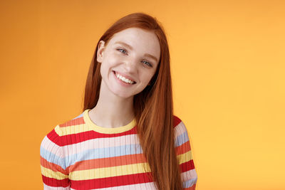 Portrait of smiling young woman against yellow background