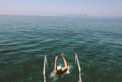 Man in jumping in sea against clear sky