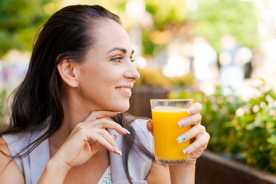 Happy business woman in street cafe drinks natural juice and smiles on sunny day. person