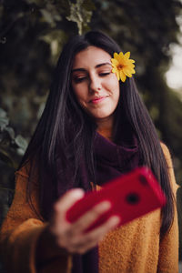 Close-up of woman taking selfie wearing flower in hair standing outdoors