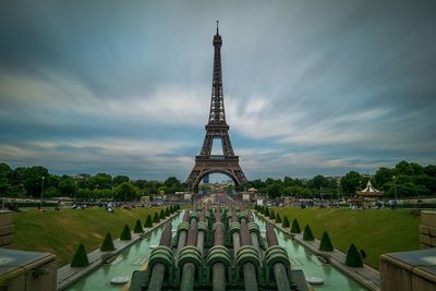 Communications tower in city against cloudy sky