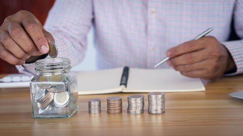 Close-up of hand holding glass jar on table