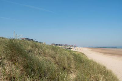 Scenic view of beach against clear blue sky