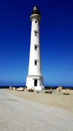 Low angle view of lighthouse by building against clear blue sky