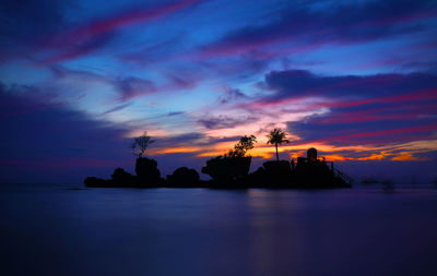 Silhouette willy rock amidst sea against cloudy sky during sunset at boracay