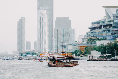 Boats in city by buildings against clear sky