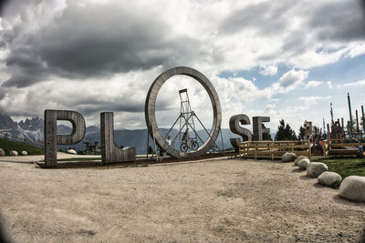 Ferris wheel on beach against cloudy sky