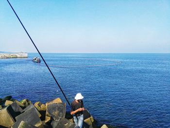 Rear view of fishing net on sea against clear sky